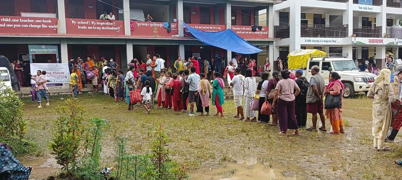 Wartende Menschen auf dem schlammigen Hof einer Schule, die als Verteilstelle dient